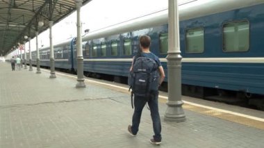 Turist backpacker tren istasyonu platformu üzerinde durmak ve tren bekliyor. Seyahat konsepti.