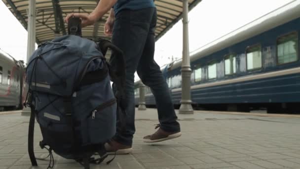 観光客は彼のバックパックを置き 出発または到着を待って 鉄道駅のプラットホームに行きます 旅行コンセプト — ストック動画
