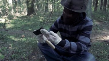 Ormanda oturan seri manyak baltayı hazırla ve kurbanı bekle. Kanlı katil, katil, korkunç maskeli çılgın adam ve iğrenç bir sırıtış. Cadılar Bayramı kostümü, korku konsepti.