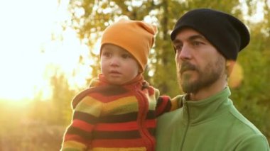 Gün batımında bir sonbahar parkında ya da ormanda bir şeye bakan genç babasının ve küçük tatlı oğlunun portresi. Sonbahar sezonunda mutlu bir aile.