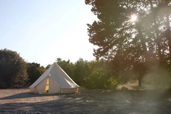 日没時に森の中でキャンプ場をグラミング 豪華な屋外休暇のための大きなキャンプテント 宿泊施設 ハイパーローカル旅行 夜のコンセプトをキャンプ スペースのコピー ロイヤリティフリーのストック写真