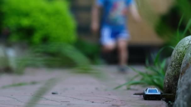 慢动作的孩子跑来跑去 坐着玩具车走了 活跃的孩子们在后院玩耍 快乐童年生活的概念 — 图库视频影像