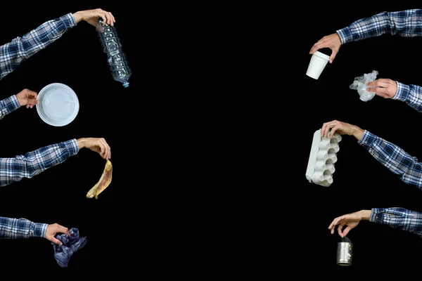 Recycling, separate waste collection, ecology garbage problem. Hands with different type of recycling rubbish on black background. Plastic, paper, organic trash.