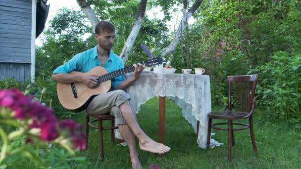 Stilig Man Vilar Trädgården Sitter Vid Bordet Och Spelar Gitarr — Stockvideo