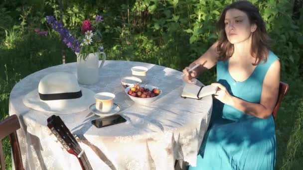 Genç Bir Kadın Arka Bahçedeki Bahçe Masasında Oturur Bir Deftere — Stok video