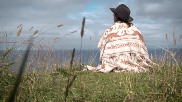 Keçeli Şapkalı Yünlü Pançolu Yalnız Bir Kadın Çimenli Deniz Kıyısında — Stok video
