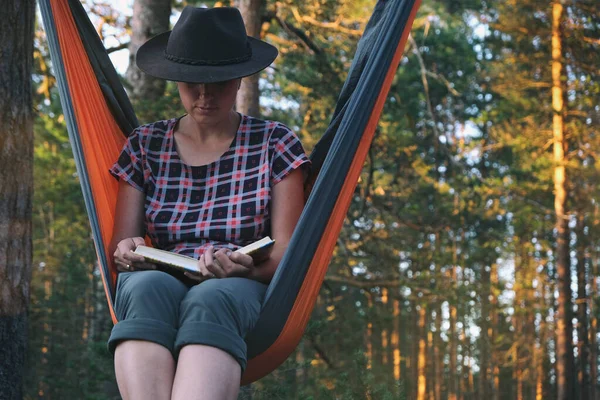 Vrouw Fedora Hoed Lezen Boek Tijdens Het Zitten Hangmat Dennenbos — Stockfoto