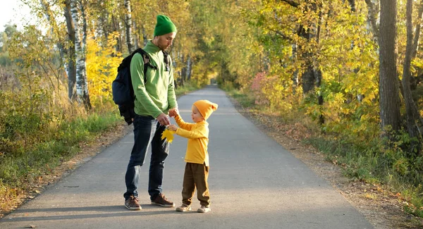 父と息子が一緒に秋の公園の空の道を歩いて 天気の良い日を楽しんでいます 秋の季節に美しい自然 子育て 幼少期 — ストック写真