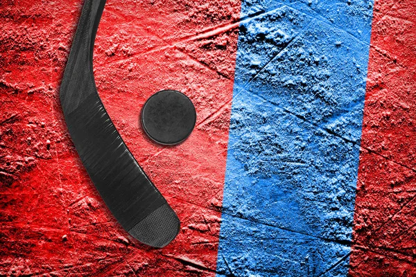 Hokejka a PUK na červeném ledu s modrým pruhem — Stock fotografie