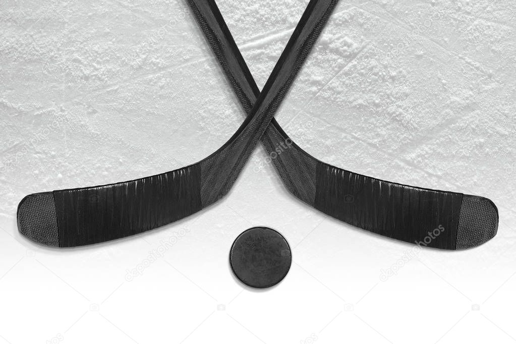Two hockey sticks and a puck on the ice