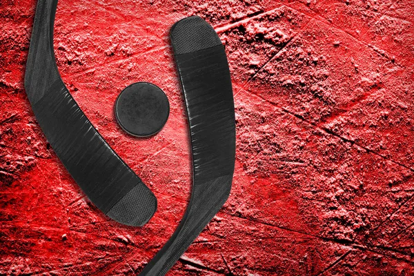 Dos palos de hockey y un disco sobre hielo rojo — Foto de Stock