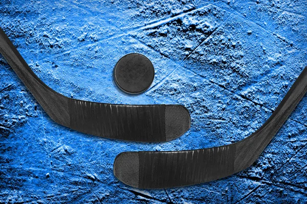 Dos palos de hockey y un disco sobre hielo azul — Foto de Stock