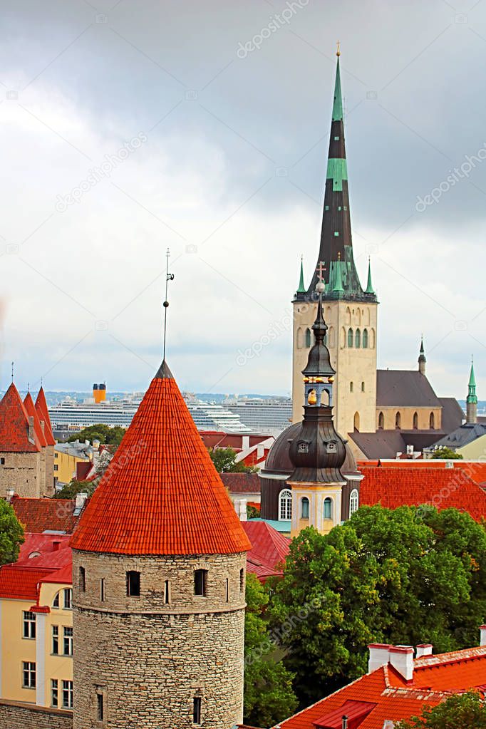The church of Oleviste (St. Olaf) close up and towers of the walls of Tallinn on a cloudy day, Tallinn, Estonia