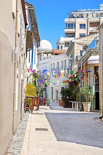 Limasol, Kıbrıs - 05 Mart 2019: Güneşli bir günde Eski kentte renkli bayraklı, kafe masaları ve sandalyeleri olan yaya caddesi — Stok fotoğraf