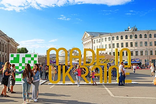 KYIV, UCRAINA - 13 LUGLIO 2019: Persone alla fiera vicino al titolo MADE IN UKRAINE, un festival di mercato di strada nel fine settimana, fiere dell'artigianato e dell'Università Nazionale di Kiev-Mohyla Academy (a destra ) — Foto Stock