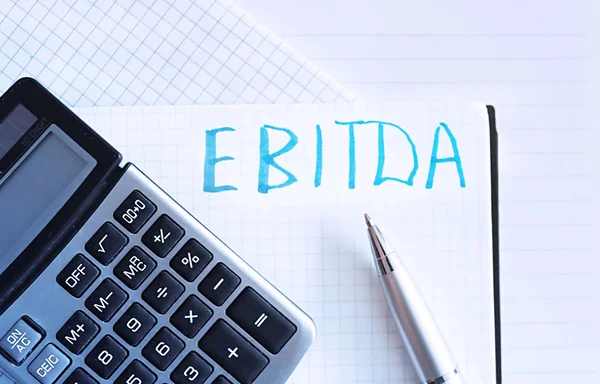 The word EBITDA is written by hand on the paper. Concept of finance Stock Picture