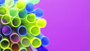 Mor arka plan üzerinde birçok çok renkli plastik kokteyl tüpleri Olağandışı üst görünümü. Parlak neon renklerde pipetler içmek. Kopya alanı. Afiş. Eko kavramı