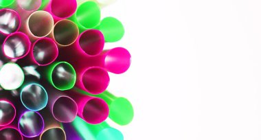 Beyaz arka plan üzerinde birçok izole çok renkli plastik kokteyl tüpleri Olağandışı üst görünümü. Parlak neon renklerde pipetler içmek. Işık efekti. Kopya alanı. Afiş. Eko kavramı