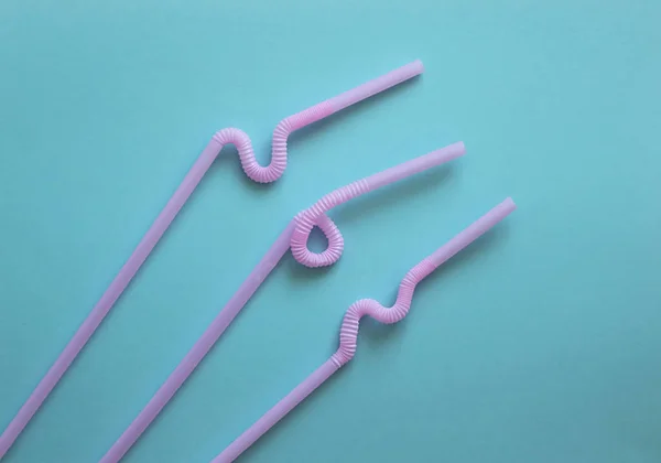 Розовые пластиковые коктейльные трубки с гибкой частью, благодаря чему они могут быть скручены в узел или зигзагом, на синем фоне. Современные и модные цвета. Эко-концепция — стоковое фото