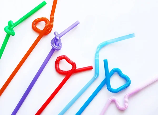 Isolated colour plastic cocktail tubes with a flexible part, due to which they can be twisted into a knot or in a zigzag, or a heart shape, on a white background. Copy space. Eco concept — Stock Photo, Image