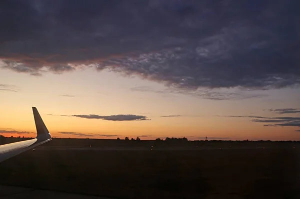 在乌克兰基辅附近的田野和跑道奥博里斯皮尔机场，五颜六色的戏剧性天空与日落的云彩。从平面查看。太阳的日落光线。飞机的机翼。着陆 — 图库照片