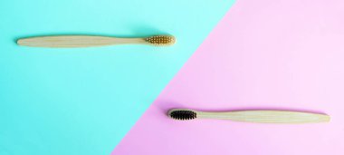 Modaya uygun mavi ve pembe renklerde iki renkli arka plan üzerinde Bambu diş fırçaları. Çevre dostu ürünler. Eko, sıfır atık ve sağlık kavramları. Düz yatıyordu. Metin için yer. Biyolojik olarak parçalanabilir malzeme