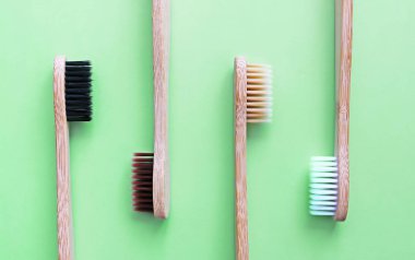 Modaya uygun yeşil arka planda bambu diş fırçaları. Çevre dostu ürünler. Eko, sıfır atık ve sağlık kavramları. Düz yatıyordu. Metin için yer. Biyolojik olarak parçalanabilir malzeme