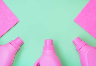 Temizlik için kimyasallarla dolu pembe plastik şişeler, temizlik için paçavralar. Hassas yeşil arka plan. Temizlik kavramı