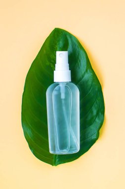 Oval yaprağın üzerinde el dezenfektanı. Açık turuncu arka plan. El dezenfektanı günlük yaşamda zorunlu hale geldi.