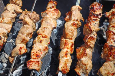Açık ateşte sulu et parçaları pişiyor.