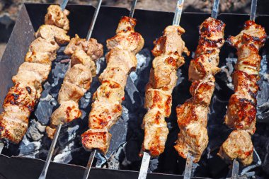 Açık ateşte sulu et parçaları pişiyor.