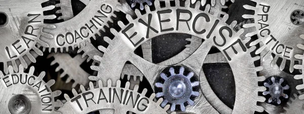 Macro photo of tooth wheel mechanism with EXERCISE concept related words and icons imprinted on metal surface