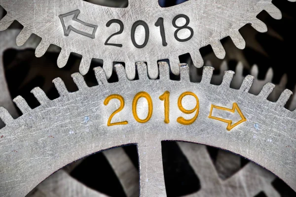 Macro photo of tooth wheel mechanism with numbers 2018, 2019 imprinted on clean metal surface; New Year concept