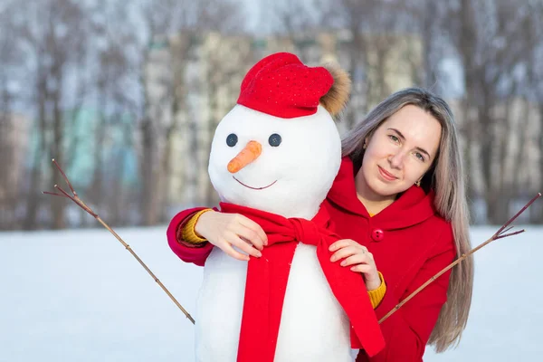 幸せな女性で赤コートとともに雪だるま — ストック写真