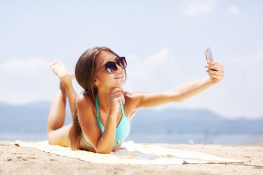 Kumsalda güneşlenirken selfie alarak güneş gözlüklü seksi kız