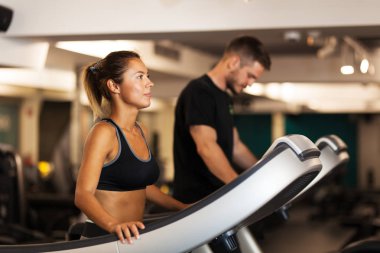 Spor salonunda koşu bandında çalışan bir çift.