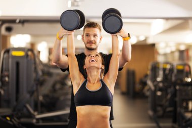 Spor koçu ağırlık kaldıran mutlu bir kız.