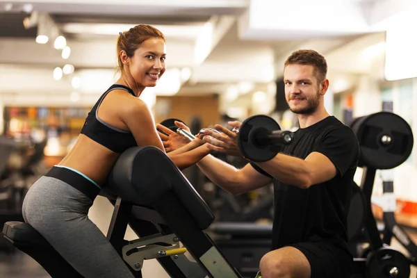 happy girl with fitness coach lifting weights