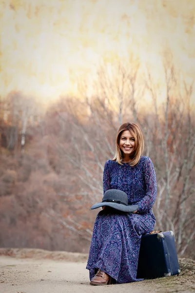 Симпатичная девушка с винтажным чемоданом на грязи — стоковое фото