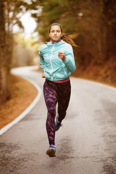 Girl running on an asphalt road — Stock Photo, Image