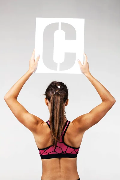 Fit girl holding the letter c — Stock Photo, Image