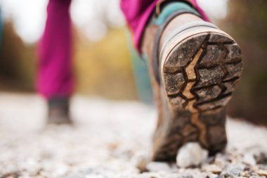 Doğa yürüyüşü yapan kız. Düşük açılı spor ayakkabıları ve çakıllı toprak yoldaki bacaklar. Açık havada sağlıklı bir yaşam tarzı..