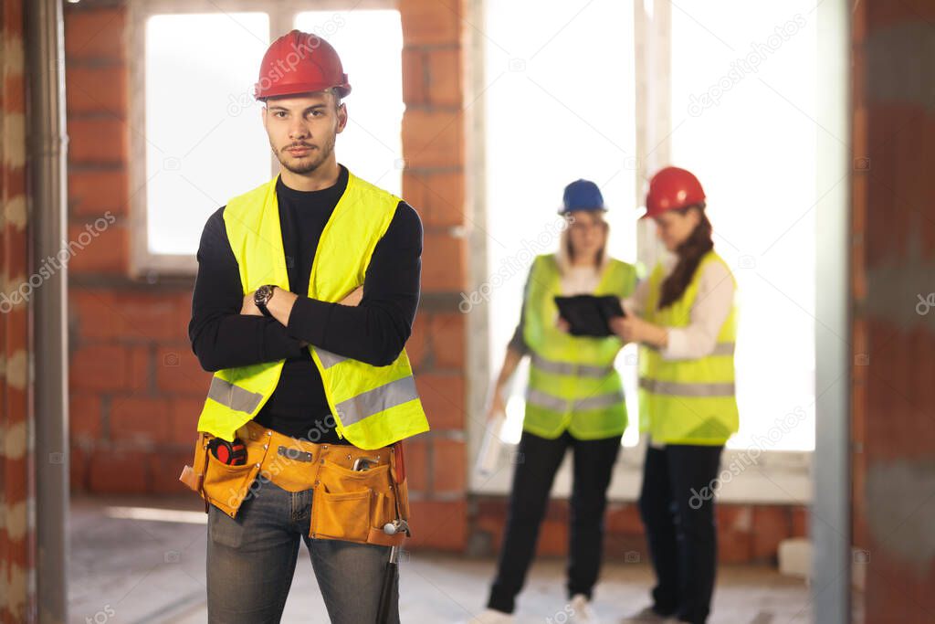 male worker on a residential construction site with his team of engineers working in the background