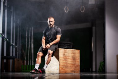 Halter ekipmanlı kaslı bir sporcu. Spor salonunda Crossfit antrenör. Duman arkaplanı.