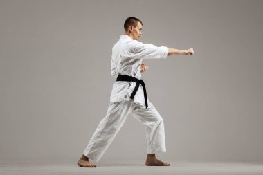 Gri arka planda karate yapan bir adam
