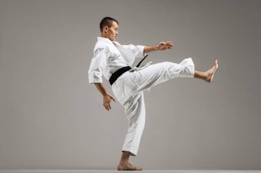 Gri arka planda karate yapan bir adam
