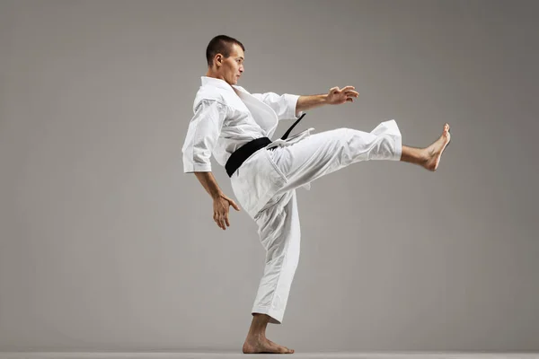 Man Utövar Karate Mot Grå Bakgrund — Stockfoto