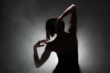 Siluet modern balerin esmer arka planda dumanla poz veriyor.