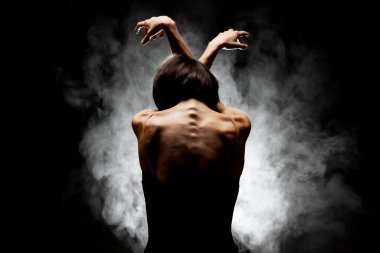 Yarı siluet modern balerin esmer arka planda dumanla poz veriyor.