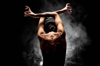 Yarı siluet modern balerin esmer arka planda dumanla poz veriyor.